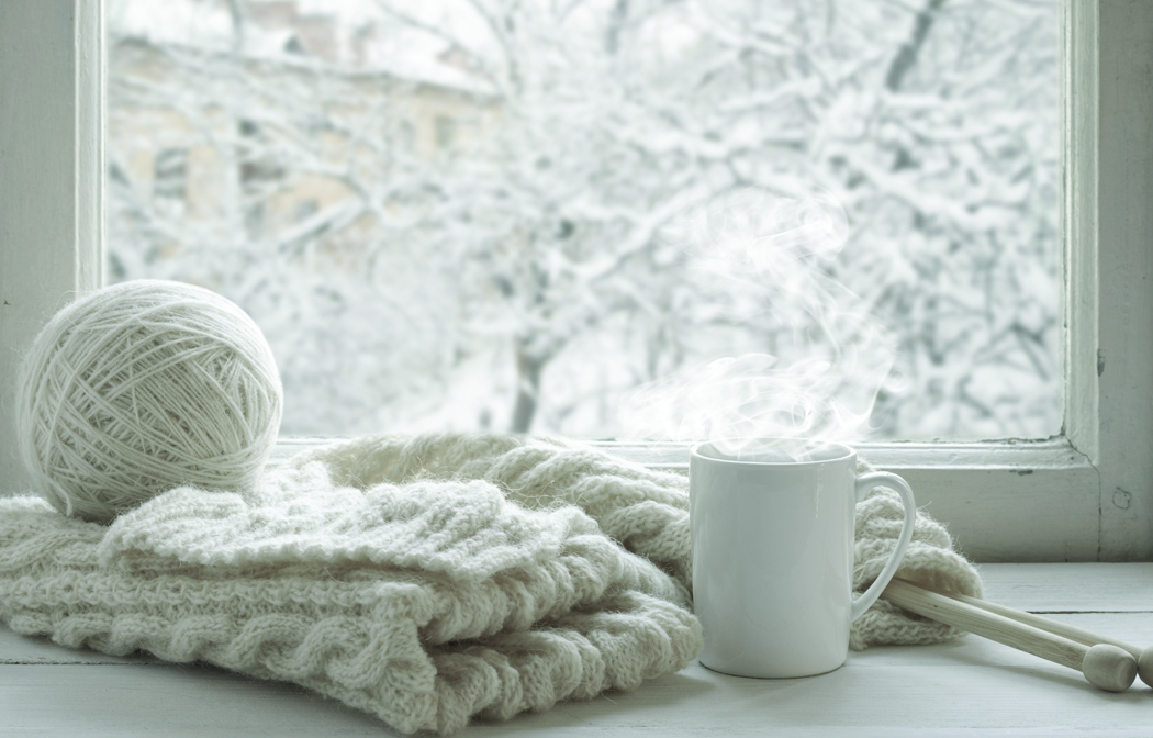 yarn, sweater, and a mug on winter background